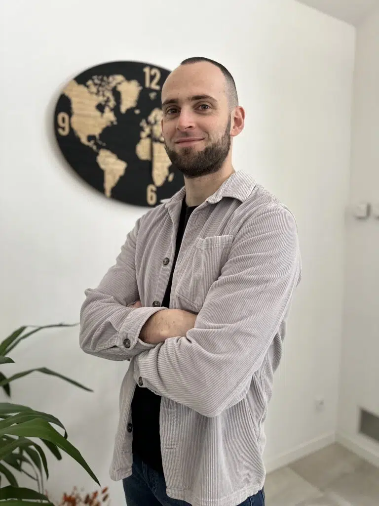 Kévin Raux, Webmaster WordPress et Consultant SEO en chemise en velours, les bras croisés en train de faire un sourire.
