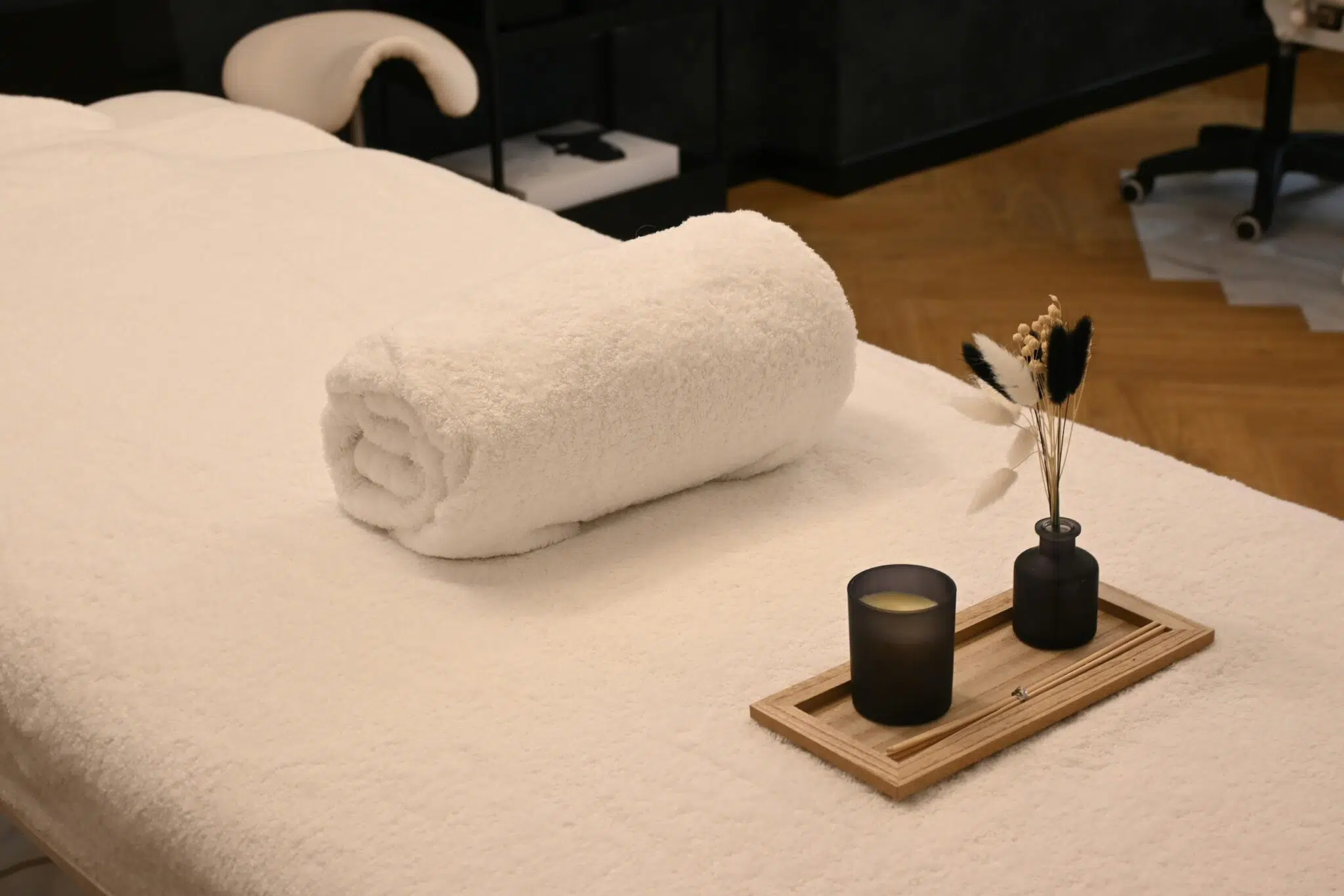 Table de massage avec une bougie et un serviette enroulée.