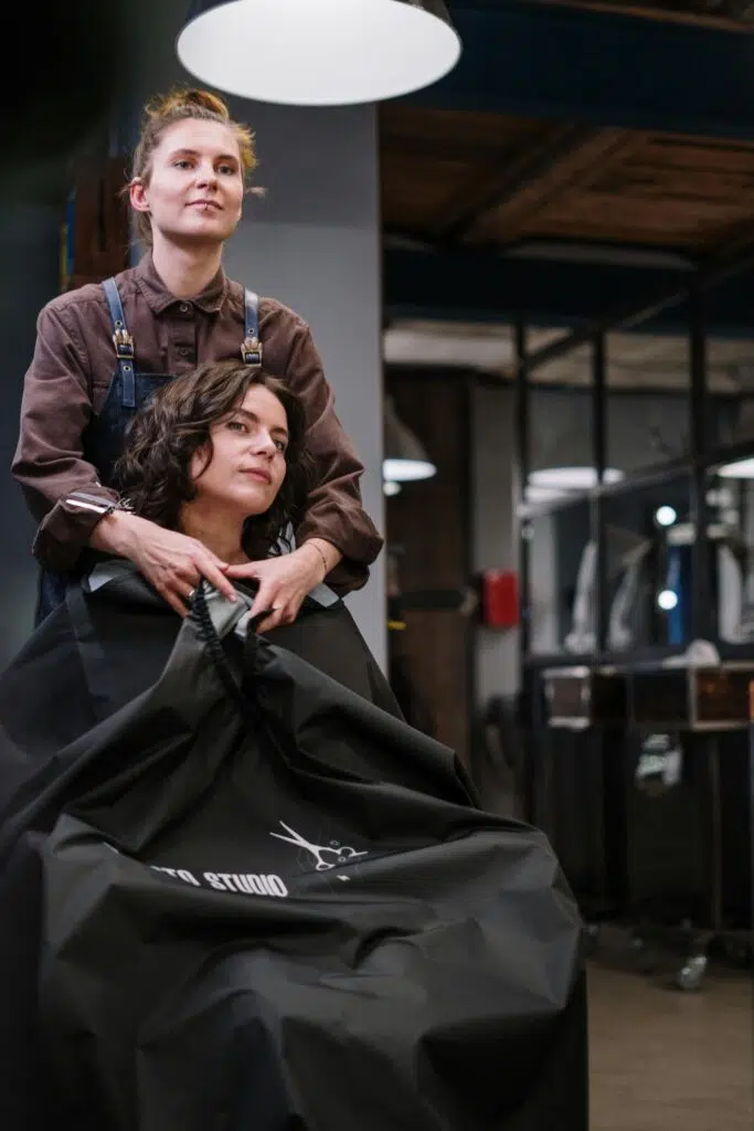 Coiffeuse travaillant sur les cheveux d'une cliente dans un salon de coiffure.