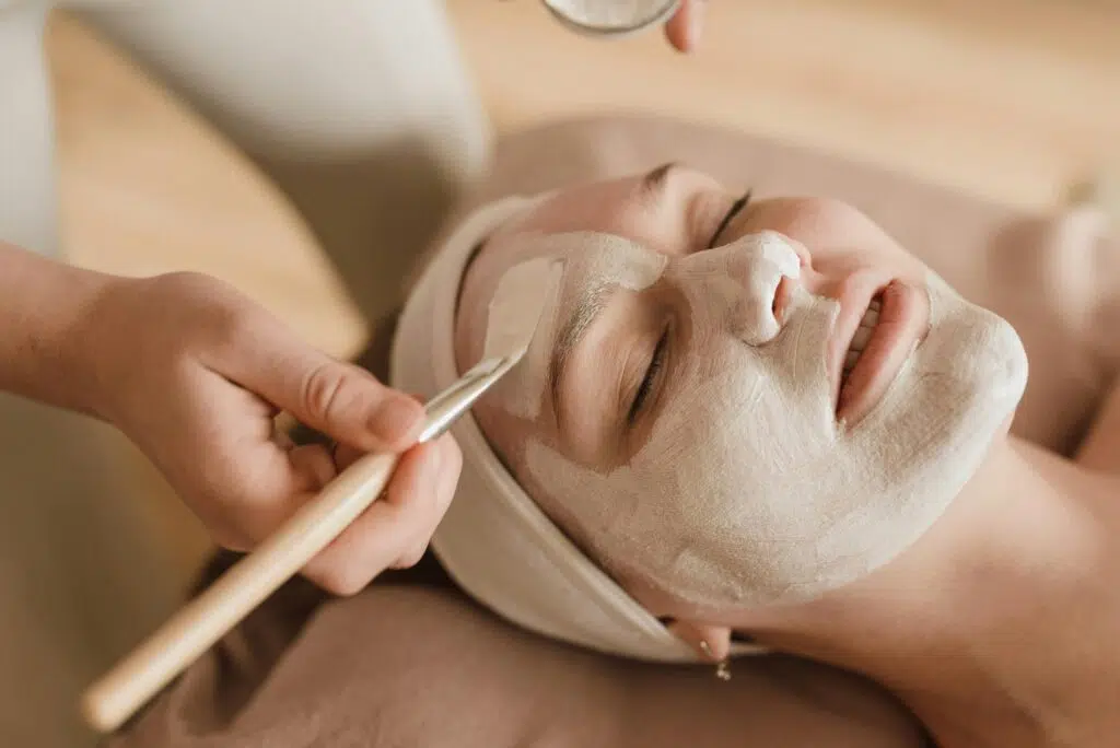 Esthéticienne appliquant un soin du visage à une cliente dans un institut de beauté.