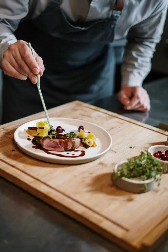Chef cuisinier dressant une assiette gastronomique en cuisine.