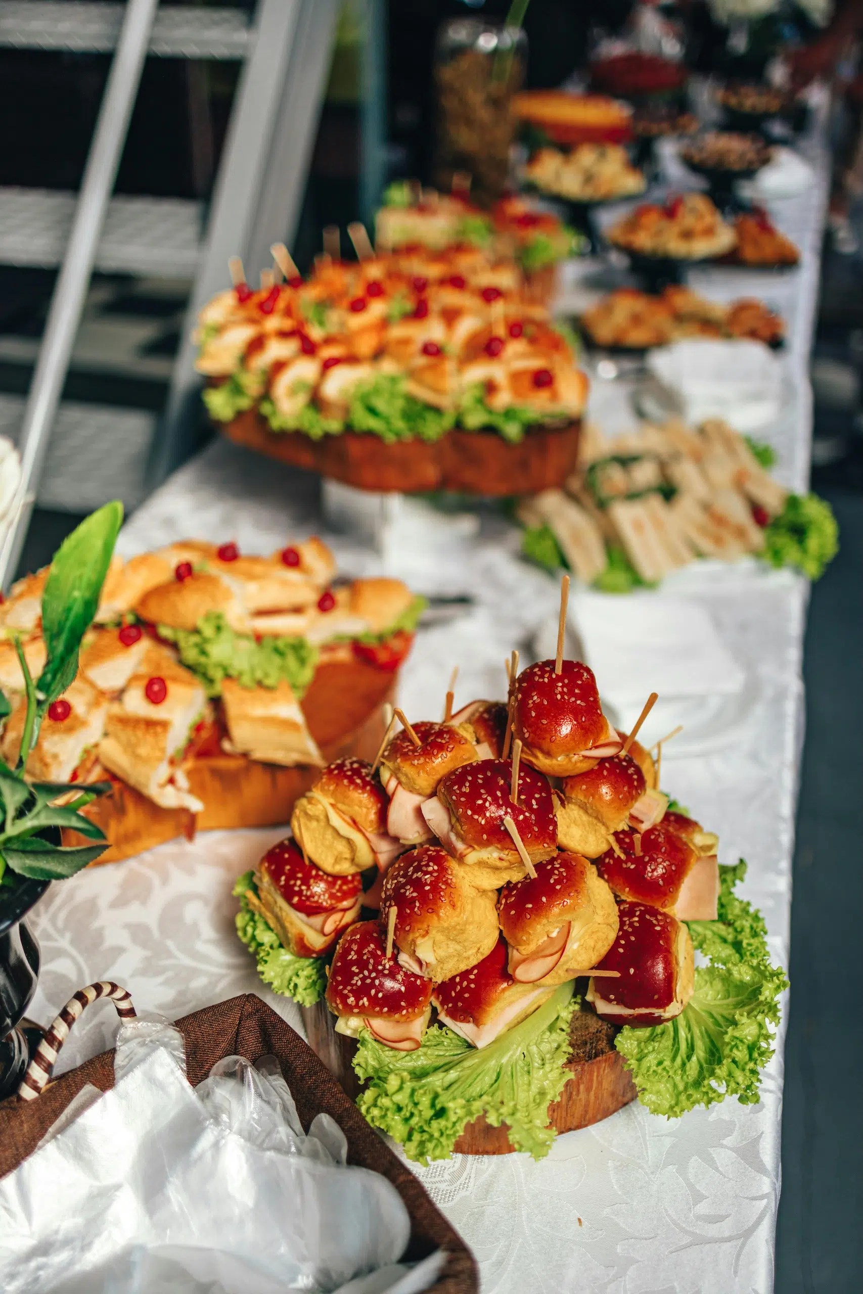 Table sur laquelle se trouve différentes bouchées apéritives comme des mini-burgers et des mini-sandwichs.