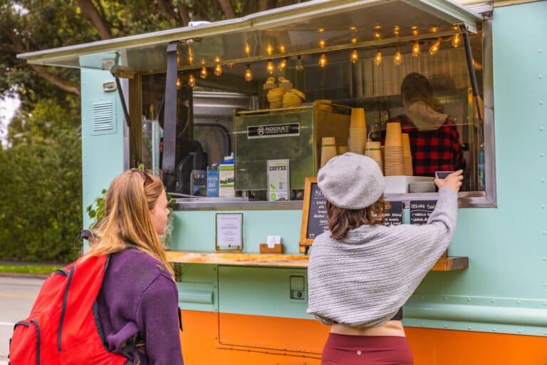 Deux clientes passant commande devant un food truck coloré vert et orange.