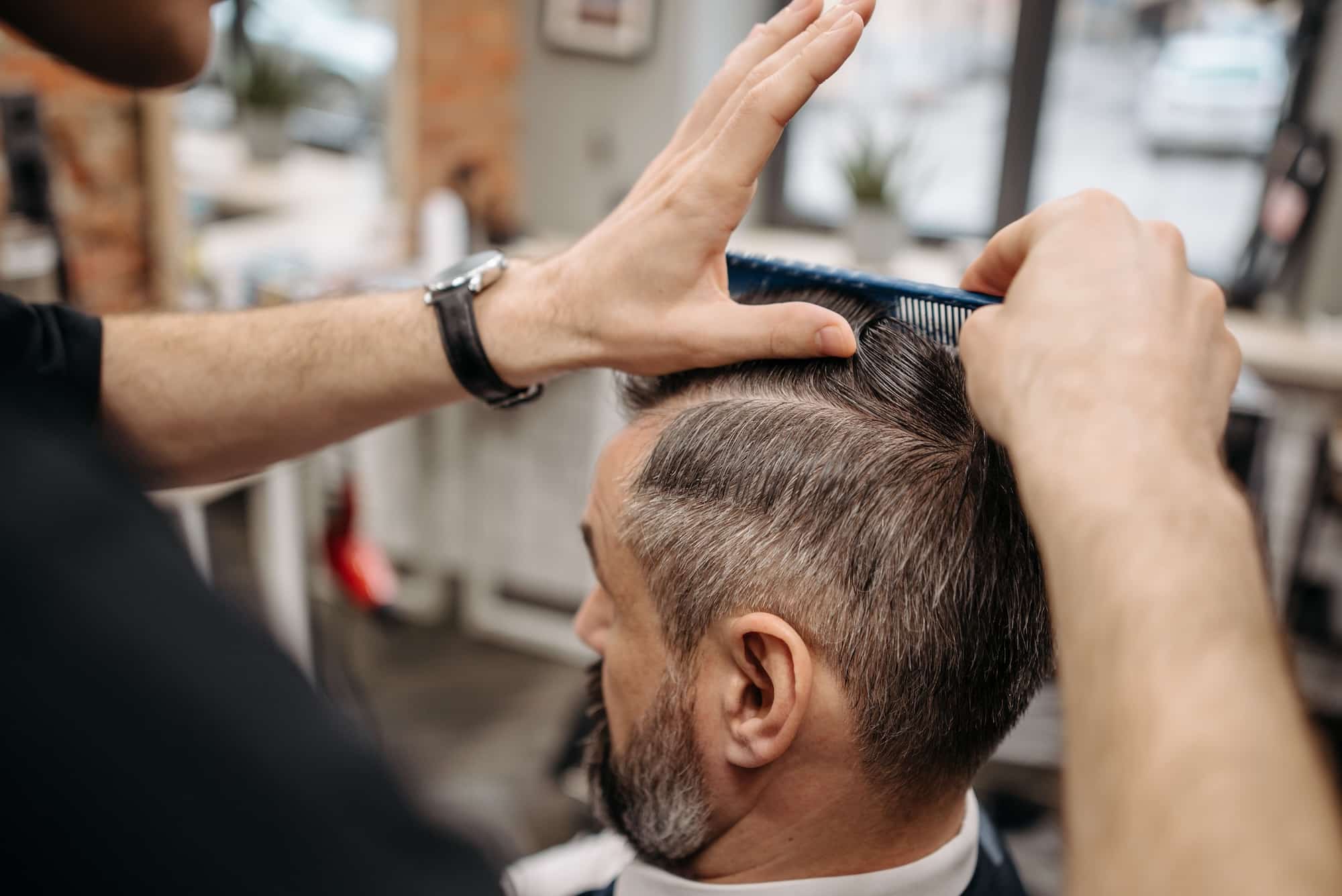 Coiffeur réalisant la coupe d'un client dans son salon.